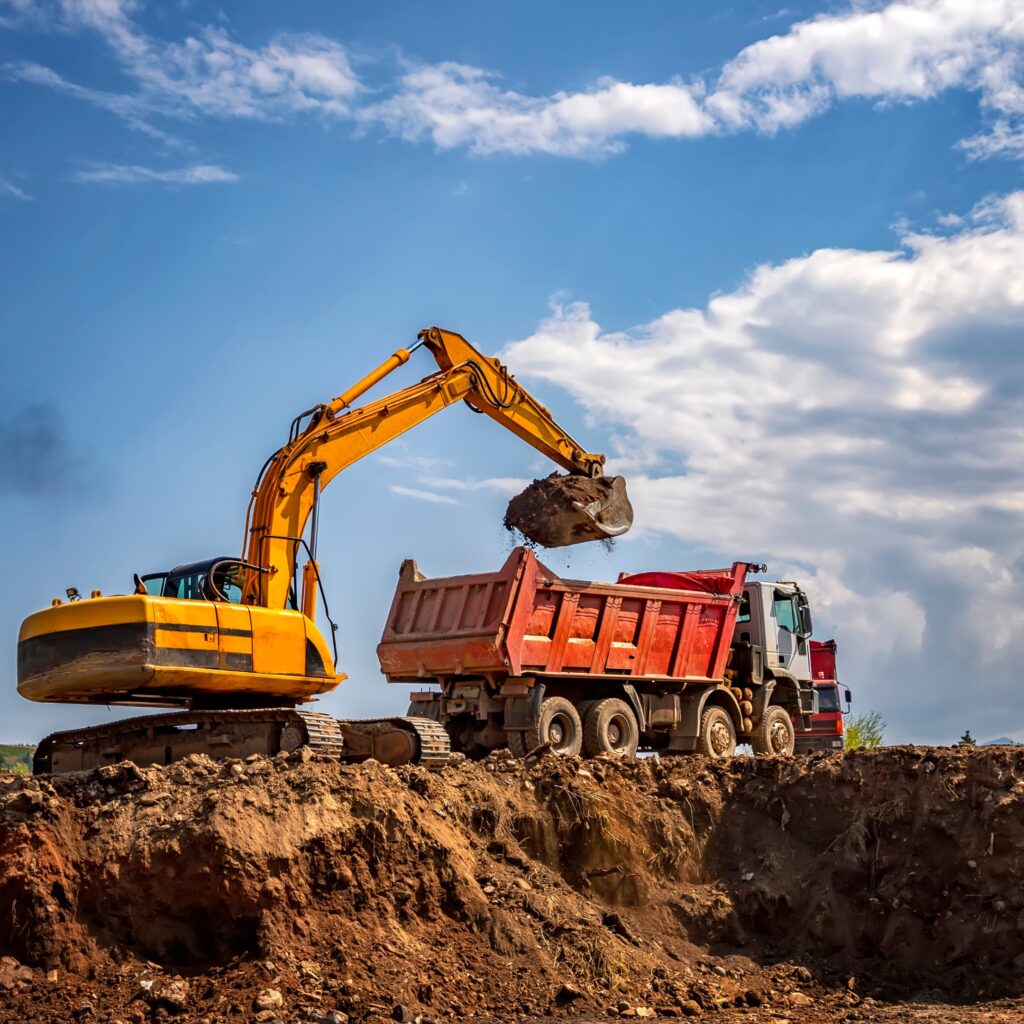 Travaux de terrassement et construction – CMK-AMS SARL. Engin de chantier chargeant un camion sur un site de construction, illustrant le savoir-faire de CMK-AMS SARL dans les services BTP : terrassement, génie civil, voirie et aménagements durables au Cameroun.
